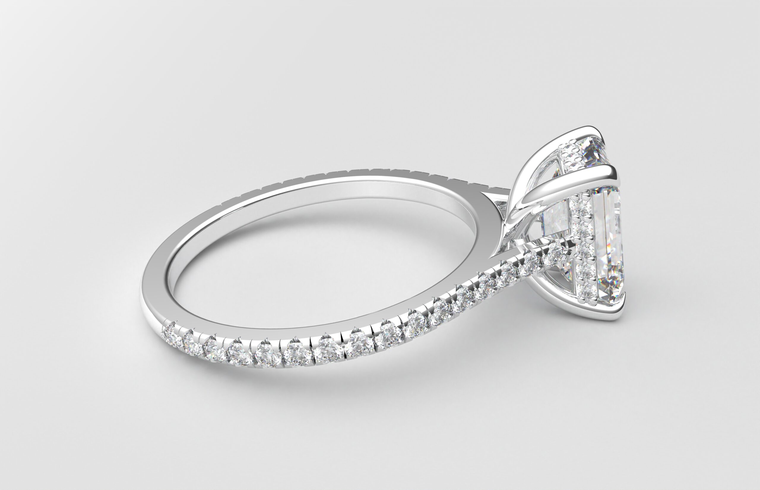 side view Cathedral setting emerald cut diamond with hidden halo ring with a simple prong setting in white gold color and french paved diamonds band