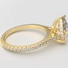 side view cathedral setting pear cut diamond with hidden halo ring with a simple prong setting in yellow gold color and french paved diamonds band