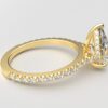 side view modern pear cathedral setting diamond with hidden halo ring with a classic prong setting in yellow gold color and french paved round diamonds band