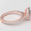 side view modern pear cathedral setting diamond with hidden halo ring with a classic prong setting in rose gold color and french paved round diamonds band