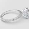 side view oval diamond with hidden halo ring with a classic 4 prong setting in white gold color and french paved diamond band