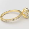 side view oval diamond with hidden halo ring with a classic 4 prong setting in yellow gold color and french paved diamond band