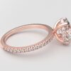 side view oval diamond with hidden halo ring with a classic 4 prong setting in rose gold color and french paved diamond band