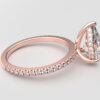 side view pear diamond with hidden halo ring with a classic 3 prong setting in rose gold color and french paved diamond band