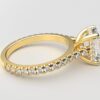 side view modern cathedral setting french pave emerald diamond ring in yellow gold with a hidden halo