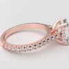 side view modern cathedral setting french pave emerald diamond ring in rose gold with a hidden halo