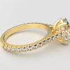 side view modern catherdral setting french pave oval diamond ring in yellow gold with a hidden halo